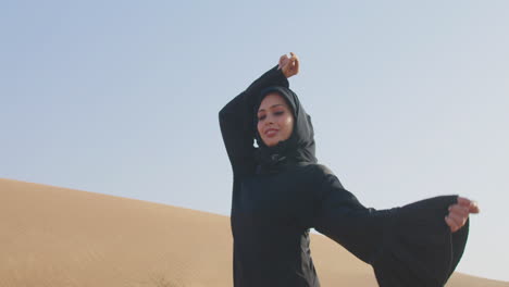 Beautiful-Muslim-Woman-Wearing-Traditional-Black-Dress-And-Hijab-Posing-In-The-Desert
