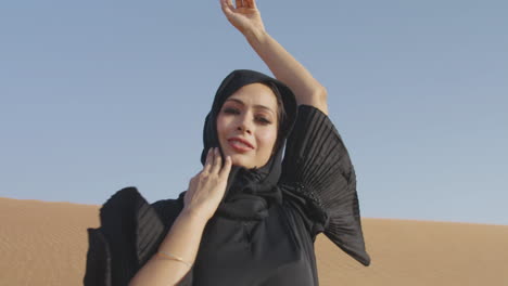 Mujer-Musulmana-Con-Vestido-Negro-Tradicional-Y-Hiyab-Posando-En-Un-Desierto-Ventoso-1
