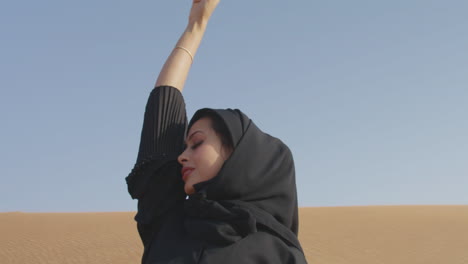 Muslimische-Frau,-Die-Traditionelles-Schwarzes-Kleid-Und-Hijab-Trägt-Und-In-Einer-Windigen-Wüste-Posiert-2