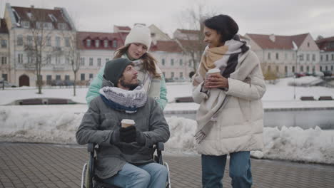 Behinderter-Mann-Im-Rollstuhl-Und-Zwei-Frauen,-Die-Im-Winter-In-Der-Stadt-Spazieren-Gehen-Und-Miteinander-Reden