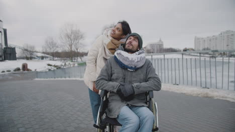 Muslimische-Frau-Und-Ihr-Behinderter-Freund,-Der-Im-Winter-Etwas-Am-Himmel-In-Der-Stadt-Betrachtet