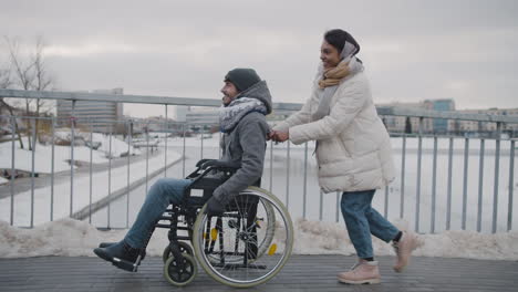 Side-View-Of-A-Muslim-Woman-Pushing-Friend-On-A-Wheelchair-On-A-Slope-1