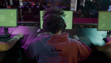 Rear-View-Of--Team-Of-Cybersport-Gamers-Playing-Virtual-Video-Games-On-Professional-Computer-With-Green-Screen-Display