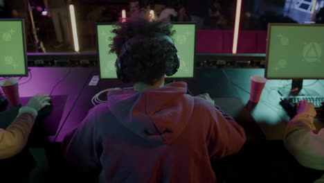 Rear-View-Of-Cybersport-Gamers-Playing-Virtual-Video-Games-On-Professional-Computer-With-Green-Screen-Display