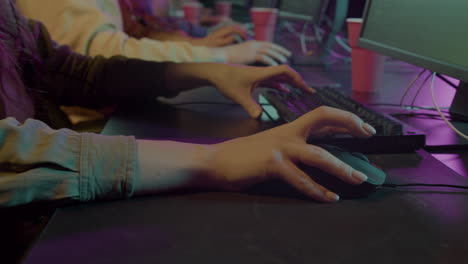 Nahaufnahme-Der-Hand-Einer-Spielerin-Auf-Einer-Computermaus,-Die-Virtuelle-Videospiele-Spielt,-Während-Sie-Mit-Ihrem-Team-Im-Gaming-Club-1-Sitzt