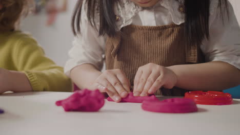 Nahaufnahme-Eines-Kleinen-Mädchens,-Das-Mit-Knete-Spielt-Und-Am-Schreibtisch-In-Einer-Montessori-Schule-Sitzt