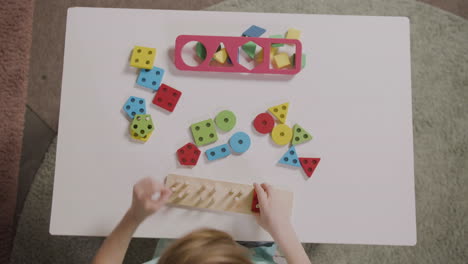 Top-View-Of-Little-Girl-Playing-With-Shapes-Stacking-In-A-Montessori-School