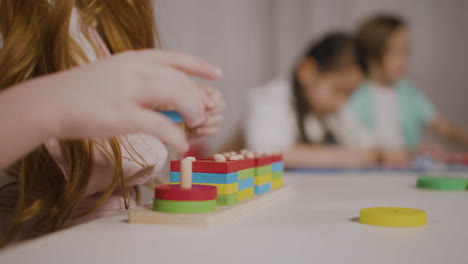 Nahaufnahme-Eines-Nicht-Erkennbaren-Roten-Mädchens-In-Einer-Montessori-Schule,-Das-Mit-Sich-Stapelnden-Formen-Spielt