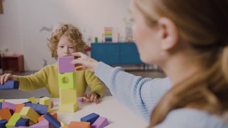 Female-Teacher-And-Blond-Little-Boy-Playing-With-Foam-Building-Blocks-In-A-Montessori-School-1