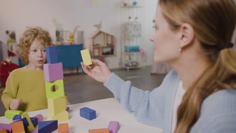 Female-Teacher-And-Blond-Little-Boy-Playing-With-Foam-Building-Blocks-In-A-Montessori-School-2