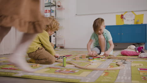 Zwei-Kleine-Jungs-Spielen-Mit-Holzautos-Auf-Dem-Teppich-Im-Klassenzimmer-In-Einer-Montessori-Schule