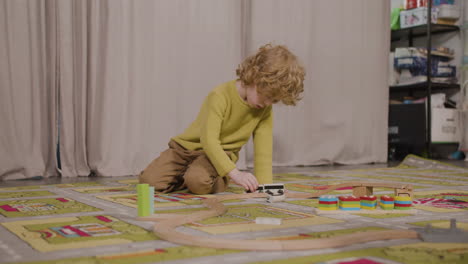 Little-Blond-Boy-Playing-With-Wooden-Cars-On-The-Carpet-In-Classroom-In-A-Montessori-School