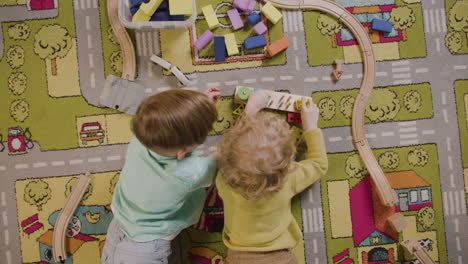 Top-View-Of-Children-Playing-With-Wooden-Pieces-Lying-On-A-Carpet-In-A-Montessori-School-Class