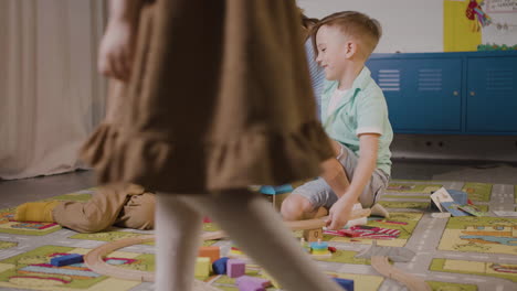 Kinder,-Die-Mit-Autos-Und-Holzstücken-Spielen,-Sitzen-Auf-Einem-Teppich-In-Einer-Montessori-Schule