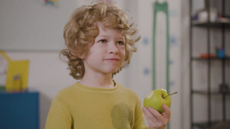 Little-Boy-Eating-An-Apple-In-Classroom-In-A-Montessori-School