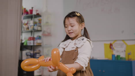 Kleines-Mädchen,-Das-Mit-Einem-Langen-Ballon-In-Form-Eines-Hundes-Im-Klassenzimmer-In-Einer-Montessori-Schule-Spielt