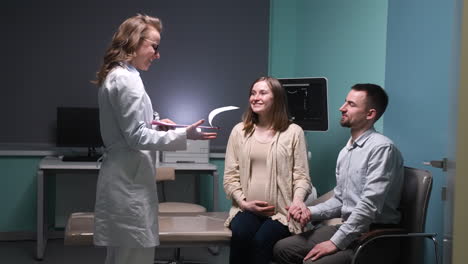 Gynäkologin-Spricht-Ihre-Schwangere-Patientin-Und-Ihren-Mann-Im-ärztlichen-Gespräch-An-Und-Informiert-Sie-über-Die-Ergebnisse-Des-Ultraschalls