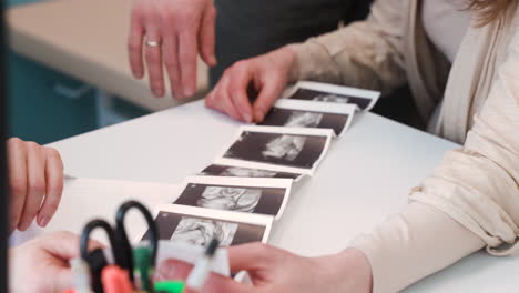 Close-Up-View-Of-Gynecologist-Showing-Ultrasound-Images-To-Her-Pregnant-Patient-In-Medical-Consultation