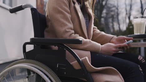 Nahaufnahme-Eines-Nicht-Erkennbaren-Behinderten-Mädchens-Im-Rollstuhl-Mit-Handy