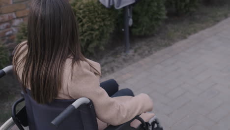 Rear-View-Of-A-Woman-Wheelchair-Turning-Around-Her-Head-And-Waving-At-Camera