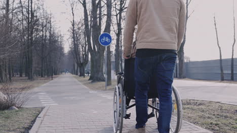 Rückansicht-Eines-Mannes,-Der-Ihre-Behinderte-Freundin-Im-Rollstuhl-Auf-Einem-Spaziergang-Durch-Die-Stadt-Mitnimmt