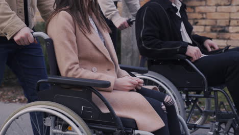 Frau-Und-Mann,-Die-Mit-Ihren-Behinderten-Freunden-Im-Rollstuhl-Durch-Die-Stadt-Spazieren-Gehen