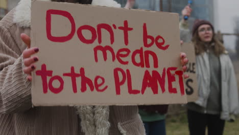 Junges-Mädchen,-Das-Während-Eines-Protestes-Gegen-Den-Klimawandel-Ein-Plakat-Aus-Pappe-Mit-Der-Phase-Dont-Be-Mean-The-Planet-Hält-1