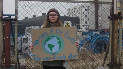 Junge-Aktivistin,-Die-Während-Eines-Protestes-Gegen-Den-Klimawandel-Ein-Plakat-Aus-Pappe-Hält,-Während-Sie-In-Die-Kamera-Schaut