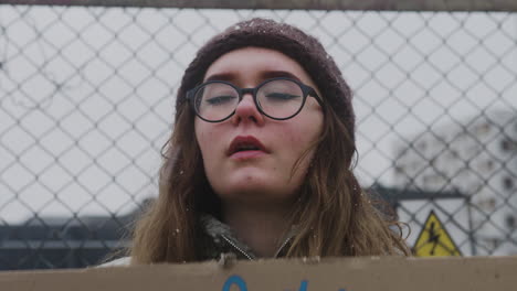 Close-Up-View-Of-Young-Female-Activist-Holding-A-Cardboard-Placard-And-Protesting-To-Save-The-Earth-During-A-Climate-Change-Protest