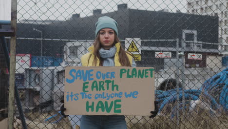 Junge-Aktivistin,-Die-Während-Eines-Protestes-Gegen-Den-Klimawandel-Ein-Plakat-Aus-Pappe-Hält,-Während-Sie-In-Die-Kamera-Blickt-2