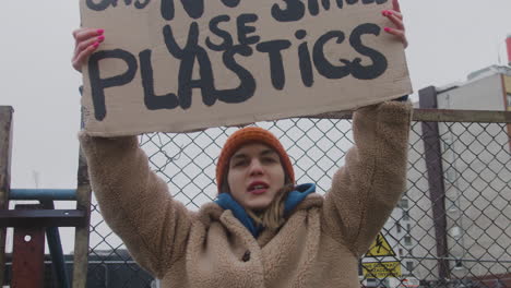 Close-Up-View-Of-Young-Female-Activist-Holding-A-Cardboard-Placard-And-Protesting-To-Save-The-Earth-During-A-Climate-Change-Protest-While-Looking-At-Camera
