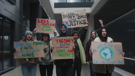 Multicultural-Group-Of-Young-Activists-Holding-Cardboard-Placards-Protesting-Against-Climate-Change-Looking-At-Camera