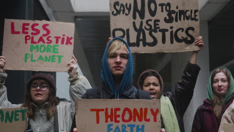 Close-Up-View-Of-Multicultural-Group-Of-Young-Activists-Holding-Cardboard-Placards-Protesting-Against-Climate-Change-Looking-At-Camera