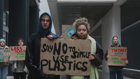 Young-Male-And-American-Female-Activists-Holding-A-Cardboard-Placard-During-A-Climate-Change-Protest-While-Looking-At-Camera-1