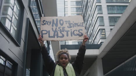 Joven-Activista-Climático-Estadounidense-Sosteniendo-Una-Pancarta-Y-Protestando-Contra-Los-Plásticos-De-Un-Solo-Uso-Mientras-Mira-La-Cámara