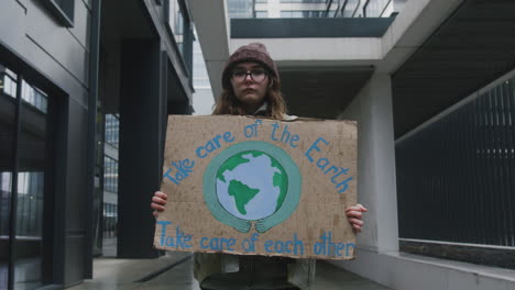Junge-Aktivistin-Mit-Banner,-Die-Einen-Stillen-Protest-Gegen-Den-Klimawandel-Macht,-Während-Sie-In-Die-Kamera-Schaut