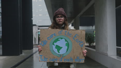 Porträt-Einer-Jungen-Aktivistin-Mit-Banner,-Die-Einen-Stillen-Protest-Gegen-Den-Klimawandel-Macht,-Während-Sie-In-Die-Kamera-Schaut