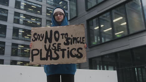 Junge-Klimaaktivistin-Mit-Banner,-Die-Gegen-Die-Einwegkunststoffe-Protestiert,-Während-Sie-In-Die-Kamera-Schaut