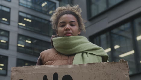 Junge-Amerikanische-Aktivistin-Mit-Einem-Plakat,-Das-Gegen-Den-Klimawandel-Protestiert,-Während-Sie-In-Die-Kamera-Schaut