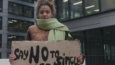 Junge-Amerikanische-Klimaaktivistin-Mit-Banner,-Die-Gegen-Die-Einwegkunststoffe-Protestiert,-Während-Sie-In-Die-Kamera-Schaut