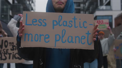 Nahaufnahme-Eines-Jungen-Männlichen-Aktivisten,-Der-Während-Eines-Protestes-Gegen-Den-Klimawandel-Ein-Plakat-Aus-Pappe-Gegen-Die-Verwendung-Von-Plastik-Hält
