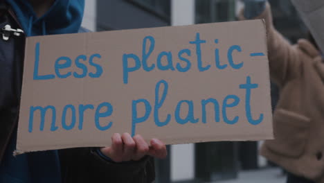 Nahaufnahme-Eines-Jungen-Aktivisten,-Der-Während-Eines-Protestes-Gegen-Den-Klimawandel-Ein-Plakat-Aus-Pappe-Gegen-Die-Verwendung-Von-Plastik-Hält