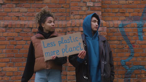 Young-Male-And-American-Female-Activists-Holding-A-Cardboard-Placards-During-A-Climate-Change-Protest