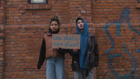 Junge-Männliche-Und-Amerikanische-Aktivisten,-Die-Während-Eines-Protestes-Gegen-Den-Klimawandel-In-Die-Kamera-Schauen-Und-Plakate-Aus-Papp-Halten