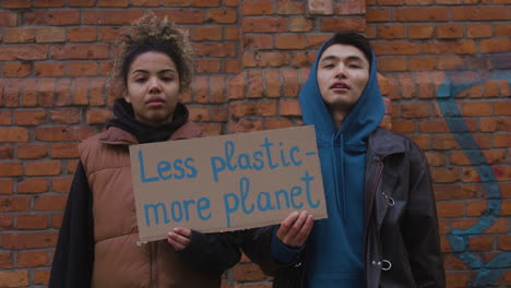 Young-Male-And-American-Female-Activists-Talking-And-Holding-A-Cardboard-Placards-During-A-Climate-Change-Protest