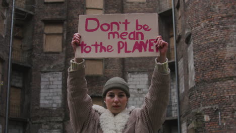 Young-Girl-Looking-At-Camera-And-Raising-A-Cardboard-Placard-With-The-Phase-Dont-Be-Mean-The-Planet-During-A-Climate-Change-Protest