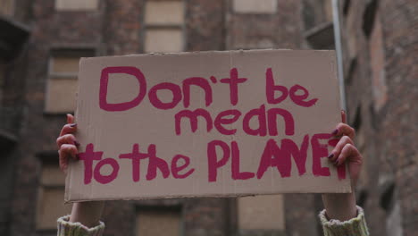 Close-Up-View-Of-A-Cardboard-Placard-With-The-Phase-Dont-Be-Mean-The-Planet-Holded-By-A-Woman-During-A-Climate-Change-Protest-1