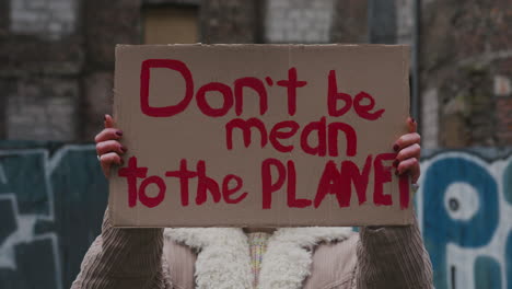 Young-Girl-Looking-At-Camera-And-Raising-A-Cardboard-Placard-With-The-Phase-Dont-Be-Mean-The-Planet-During-A-Climate-Change-Protest-1