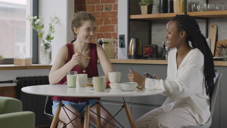 Two--Female-Roommates-Having-Breakfast-And-Talking-Together-At-Home-1