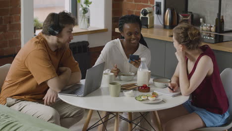 Tres-Compañeros-Sentados-En-La-Cocina-Y-Hablando-Juntos-Durante-El-Desayuno